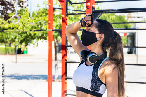 Fitness girl with a tired gesture in a calisthenics park