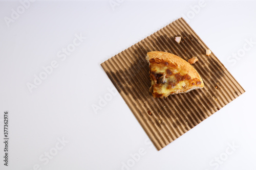 A slice of pizza on a paper liner on white background 