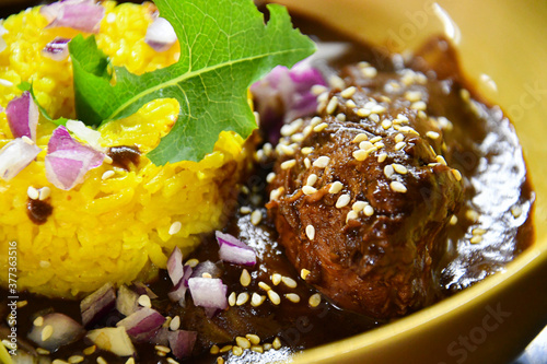 Pollo en mole, mole es una salsa mexicana hecha con chiles asados, chocolate y nueces. con  arroz con cúrcuma. 