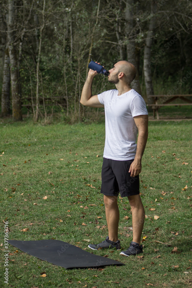 Young men drinking water from the training bottle after the workout. Young men drinking water from the training bottle after the workout.