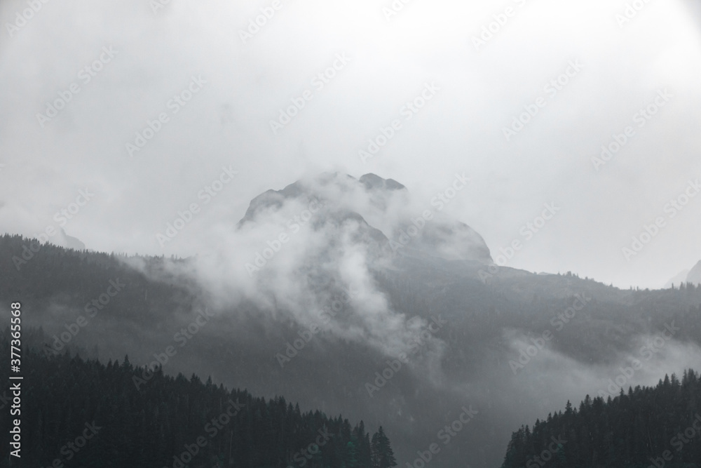 Black and white photo of a high rocky mountain in the clouds