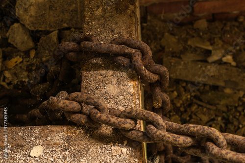 A badly corroded chain laid across the rim of a metal box.