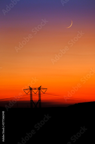 Sunset and Moon with Power Lines on Horizon