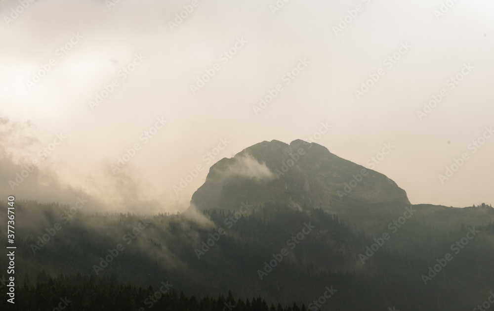 Fototapeta premium Very high mountain in the clouds, peak in the haze, montenegro, panorama
