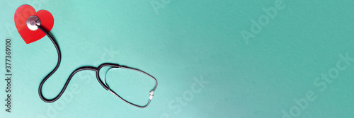 Stethoscope and red heart on green background. Top view. Banner. Copy space. Place for text.