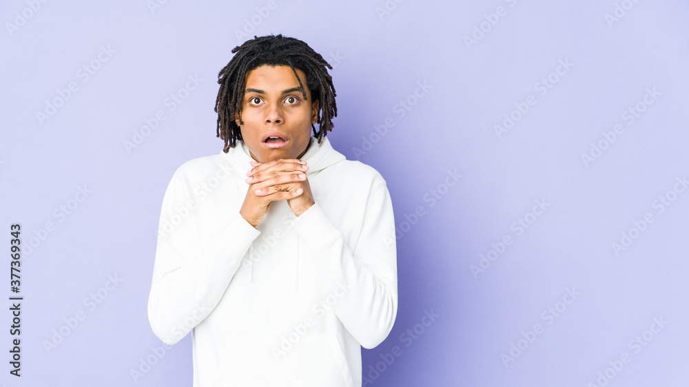Young african american rasta man praying for luck, amazed and opening mouth looking to front. Young african american rasta man praying for luck, amazed and opening mouth looking to front.
