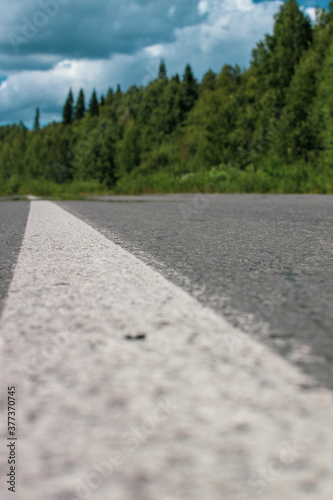 Long white stripe as road markings. The road to the distance.