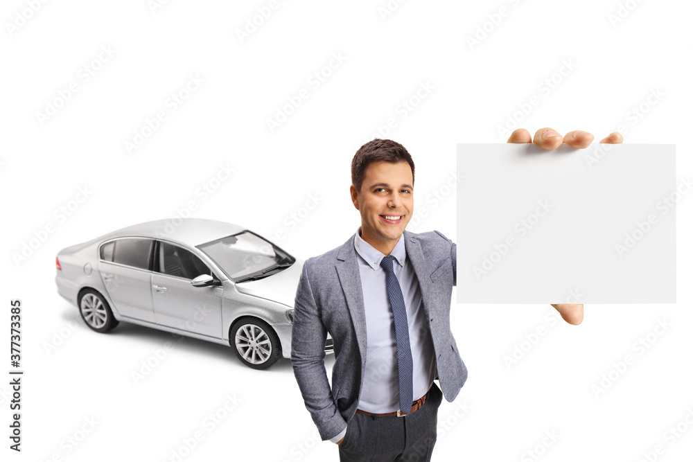 Professional young man with a silver car showing a blank card in front of the camera Professional young man with a silver car showing a blank card in front of the camera