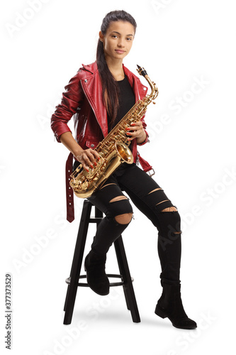 Full length portrait of a young woman sitting on a chair and holding a saxophone