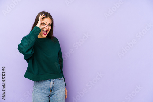 Young caucasian woman isolated on purple background excited keeping ok gesture on eye. © Asier
