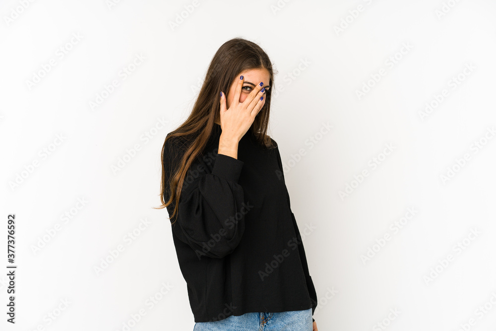 Young caucasian woman isolated on white background blink at the camera through fingers, embarrassed covering face. Young caucasian woman isolated on white background blink at the camera through fingers, embarrassed covering face.