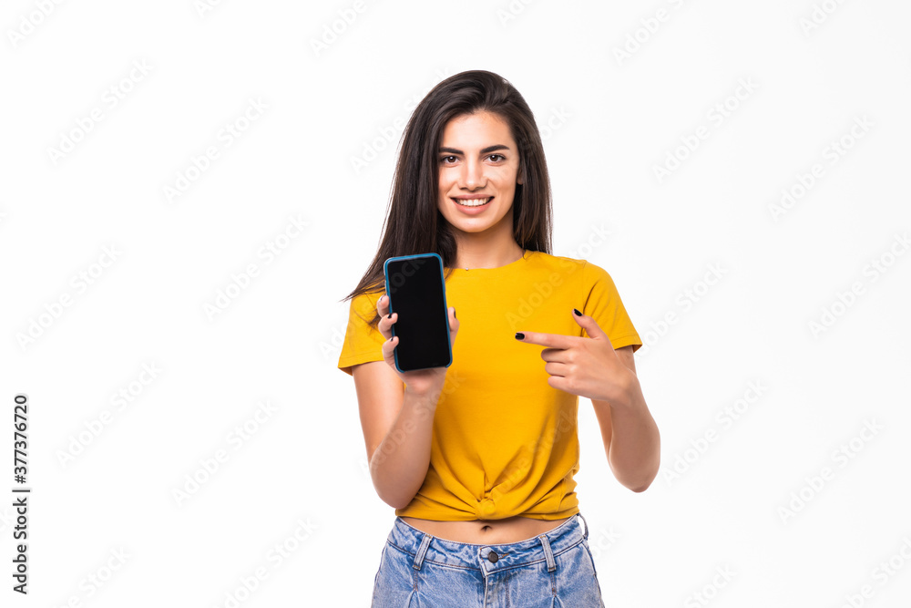 Young pretty smiling woman pointing with finger on phone screen, over white background Young pretty smiling woman pointing with finger on phone screen, over white background