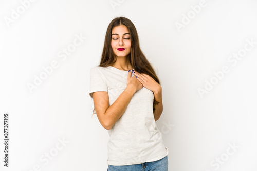 Young caucasian woman isolated on white background has friendly expression, pressing palm to chest. Love concept. © Asier