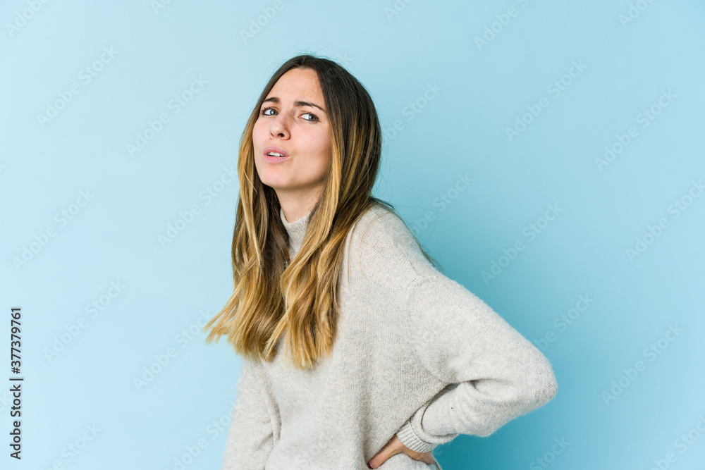 Young caucasian woman isolated on blue background suffering a back pain. Young caucasian woman isolated on blue background suffering a back pain.