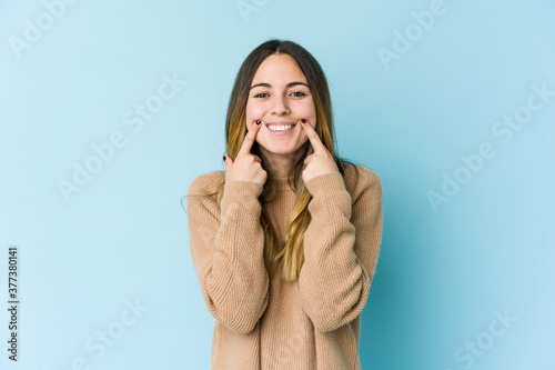 Young caucasian woman isolated on blue background doubting between two options.