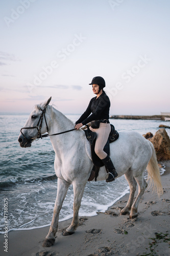 white horse with a woman riding on the beach