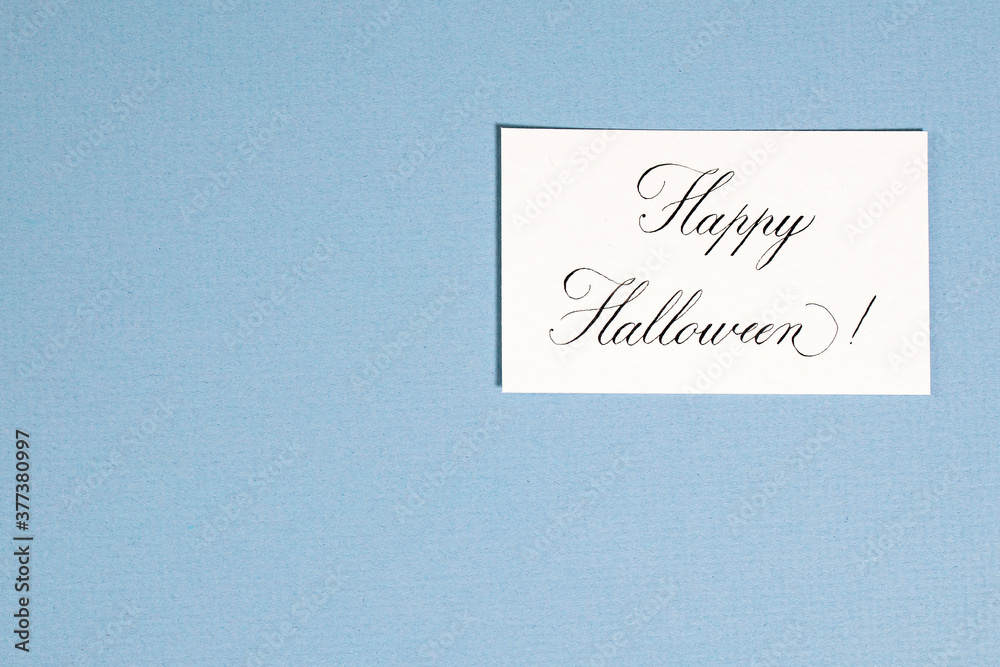 Calligraphic inscription Happy halloween on white textured paper, on blue paper card Calligraphic inscription Happy halloween on white textured paper, on blue paper card