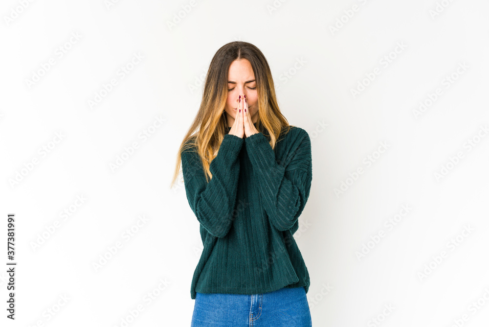 Young caucasian woman isolated on white background praying, showing devotion, religious person looking for divine inspiration. Young caucasian woman isolated on white background praying, showing devotion, religious person looking for divine inspiration.