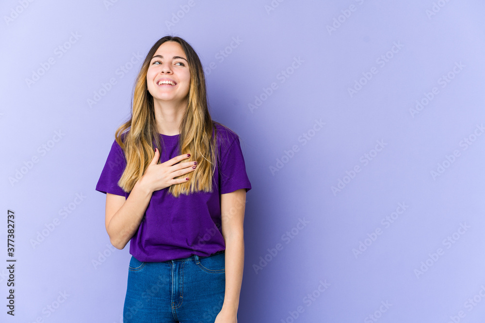 Young caucasian woman isolated on purple background laughs out loudly keeping hand on chest. Young caucasian woman isolated on purple background laughs out loudly keeping hand on chest.