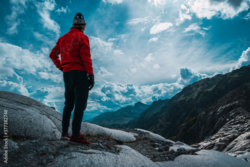 Chico con chaqueta roja en montañas de un glaciar