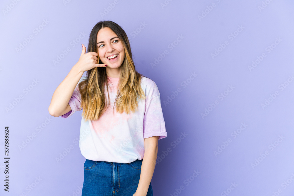 Young caucasian woman isolated on purple background showing a mobile phone call gesture with fingers. Young caucasian woman isolated on purple background showing a mobile phone call gesture with fingers.