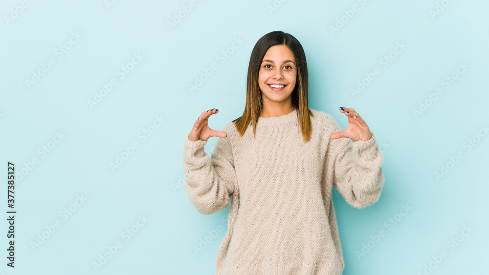 Young woman isolated on blue background holding something with palms, offering to camera. Young woman isolated on blue background holding something with palms, offering to camera.