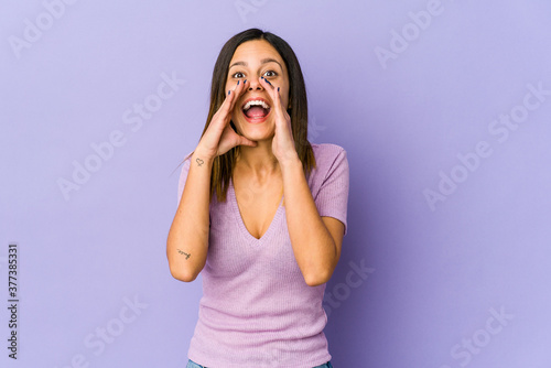 Young woman isolated on purple background shouting excited to front.