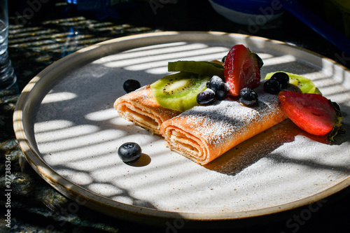 Panqueques en rollo con frutas y con polvo de azúcar photo