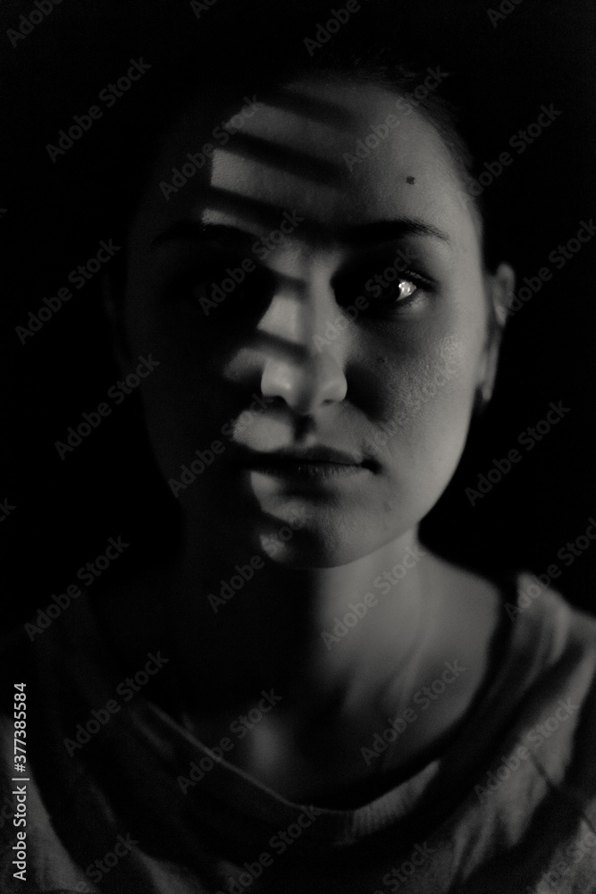 Monochrome portrait of a woman with a light mask on her face
