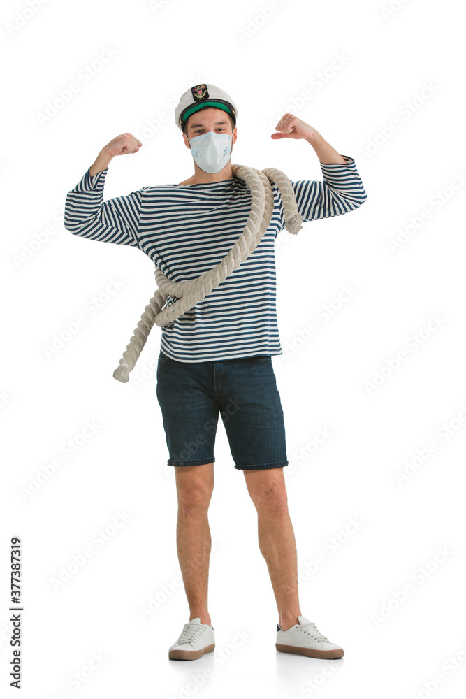 Strong, healthy. Caucasian male sailor in uniform on white studio background. Young man using modern devices, binoculars, wearing face mask. Concept of tech, professional occupation, job of seaman. Strong, healthy. Caucasian male sailor in uniform on white studio background. Young man using modern devices, binoculars, wearing face mask. Concept of tech, professional occupation, job of seaman.