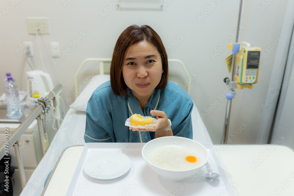 Patient and hospital concept - Asia woman patient with iv solution eating food for patient on bed in hospital Patient and hospital concept - Asia woman patient with iv solution eating food for patient on bed in hospital