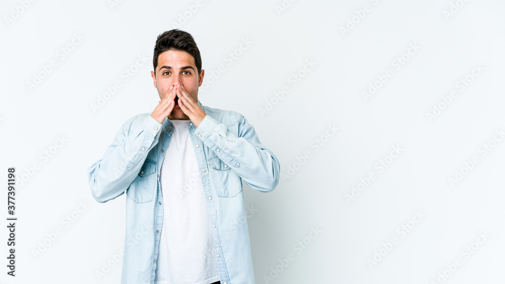 Young caucasian man isolated on white background shocked covering mouth with hands.