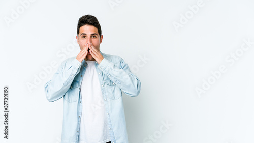 Young caucasian man isolated on white background shocked covering mouth with hands.