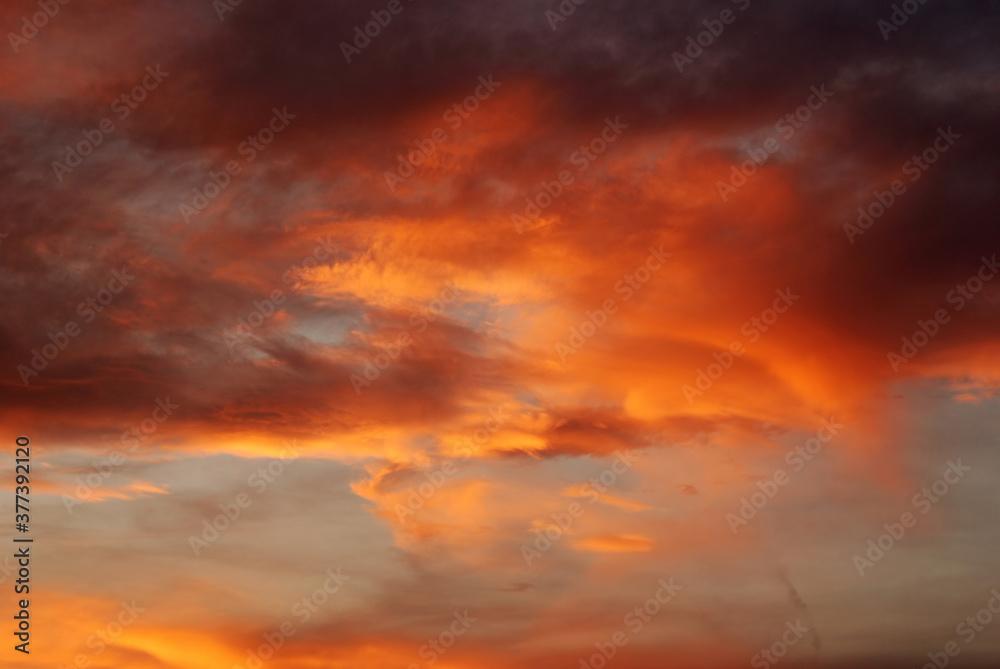 Dark blood red sky background. Dramatic heavy clouds with the hint of the sun at sunset. Many orange tones and patterns of clouds