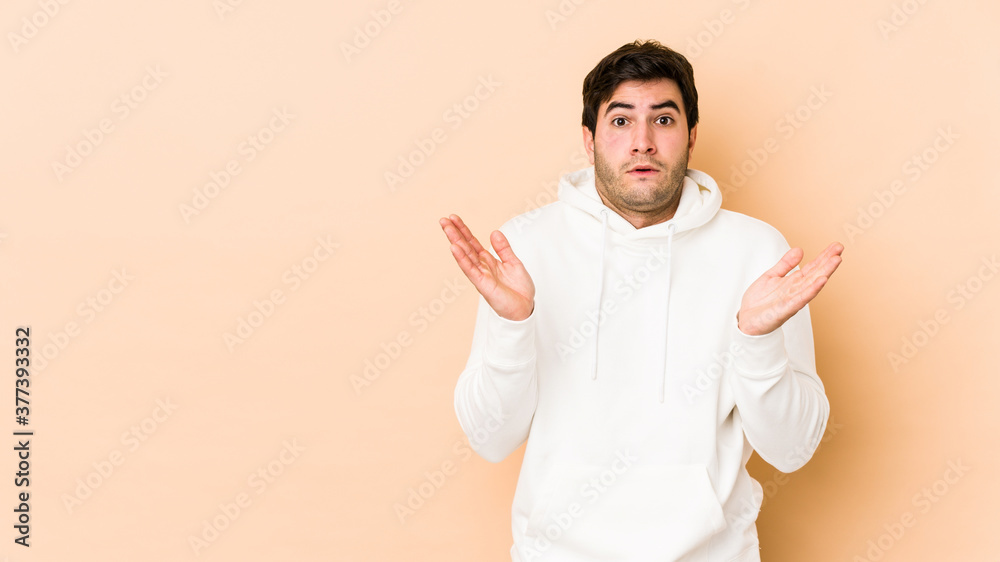 Young man isolated on beige background surprised and shocked. Young man isolated on beige background surprised and shocked.