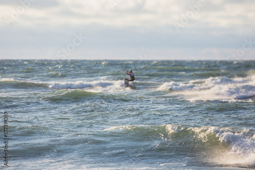 Professional kite surfer kite boarder rides the waves in the open sea, with a water splash, kitesurfing, kiteboarding extreme fun water sport in the summer sunny day