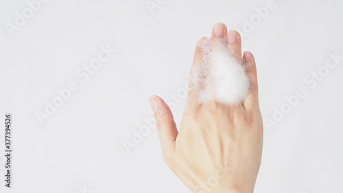 Hand washing gesture with foaming hand soap on white background.
