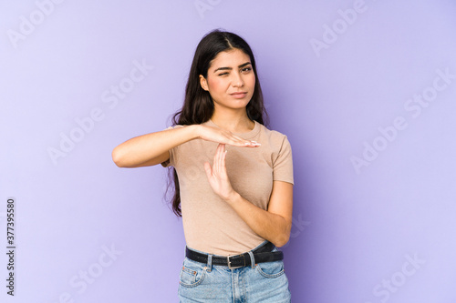 Young indian woman isolated on purple background showing a timeout gesture.
