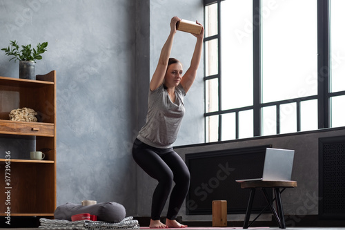 Obraz na plátně Caucasian woman doing Utkatasana, Chair Pose using block at home during online lesson