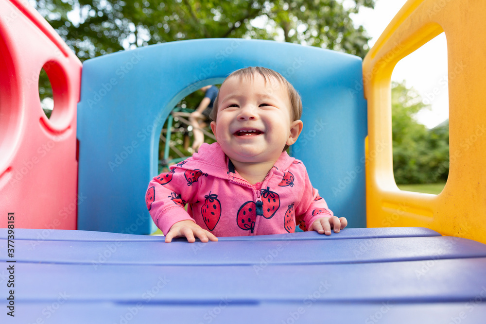 Joyful smiling toddler girl standing in colorful backyard playset Joyful smiling toddler girl standing in colorful backyard playset