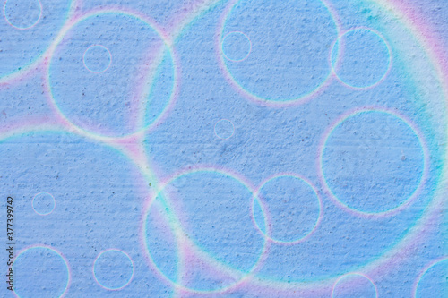 The concrete wall is blue with rainbow circles on it in a chaotic order