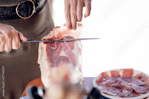 woman cutting iberian pork ham with a ham holder and knife