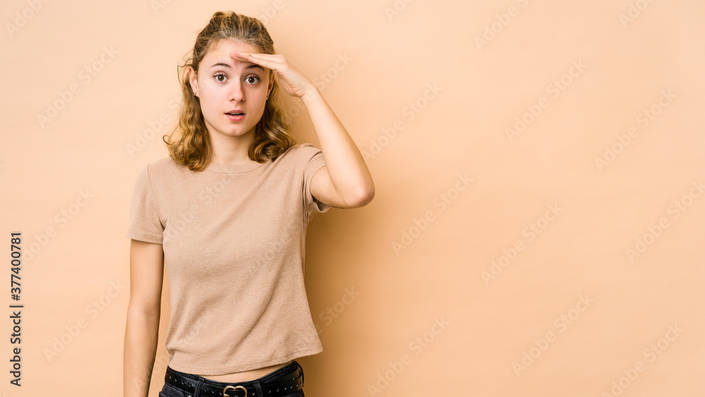 Young caucasian woman isolated on beige background looking far away keeping hand on forehead. Young caucasian woman isolated on beige background looking far away keeping hand on forehead.
