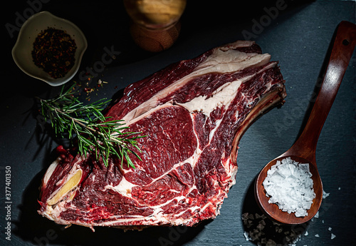 Raw steak, rosemary and salt on a serving board photo