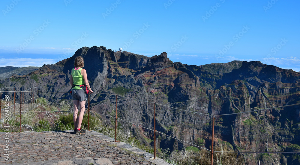 A hiker standing on the mountain top of Pico Ruivo, looking to Pico do Arieiro. Madeira, Portugal.