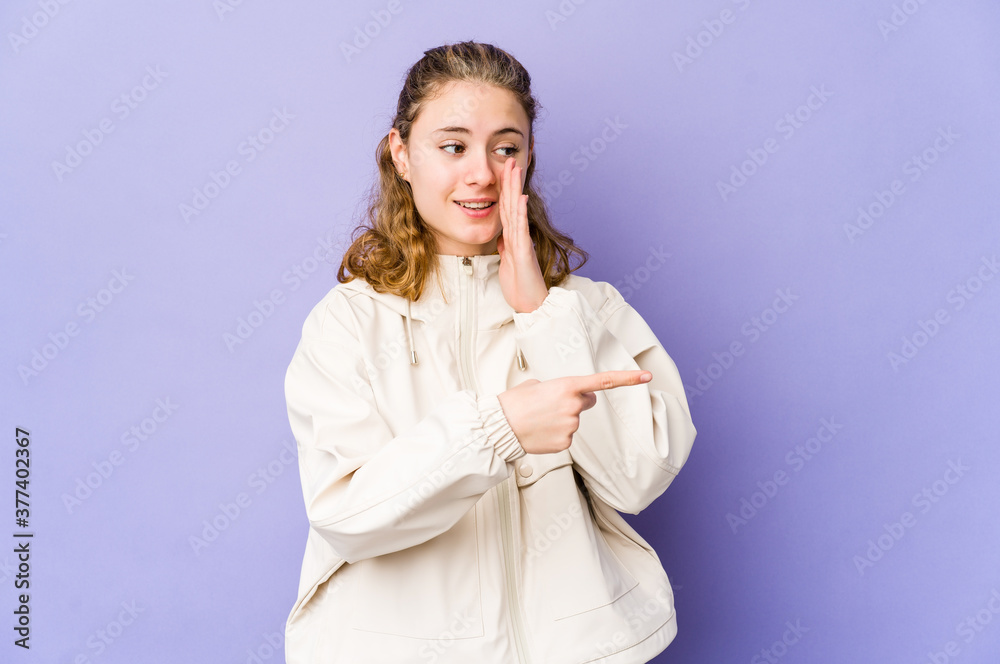 Young caucasian woman on purple background saying a gossip, pointing to side reporting something. Young caucasian woman on purple background saying a gossip, pointing to side reporting something.