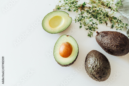 Top view of hass avocado and thyme on white background, healthy food photo