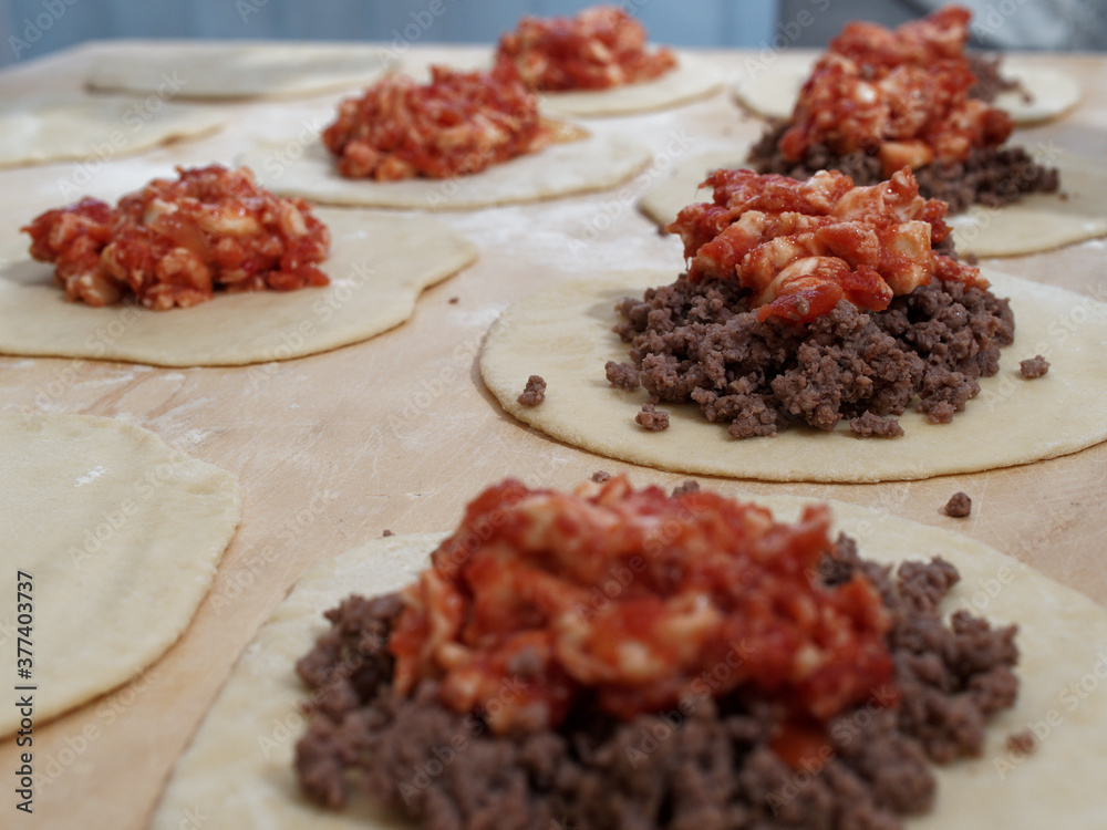 Preparations for a panzerotto, a specialty of southern Italian cuisine. Minced meat, mozzarella and tomato poured as a filling on the dough. Preparations for a panzerotto, a specialty of southern Italian cuisine. Minced meat, mozzarella and tomato poured as a filling on the dough.