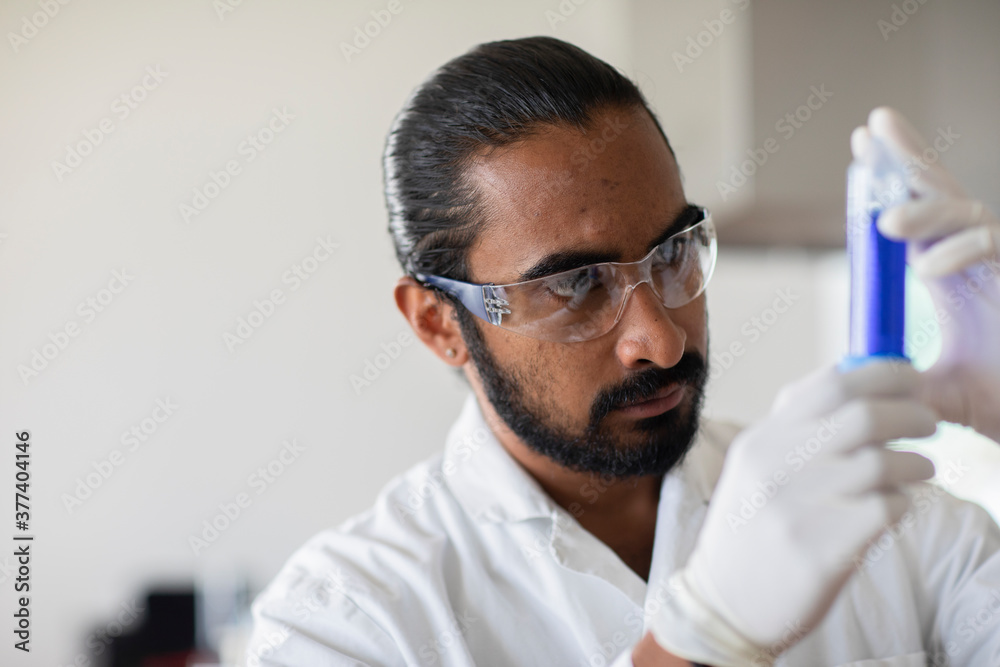 young man scientist with lab coat checking a sample young man scientist with lab coat checking a sample