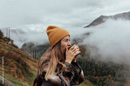 Portrait of woman traveling and exploring nature, preparing tea in a high place. photo